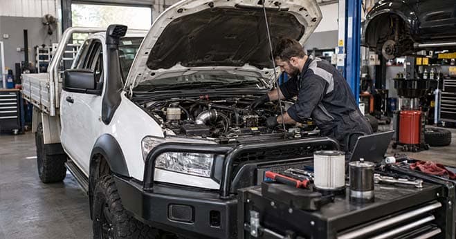 Mechanic inspecting a diesel engine under the bonnet of a utility vehicle